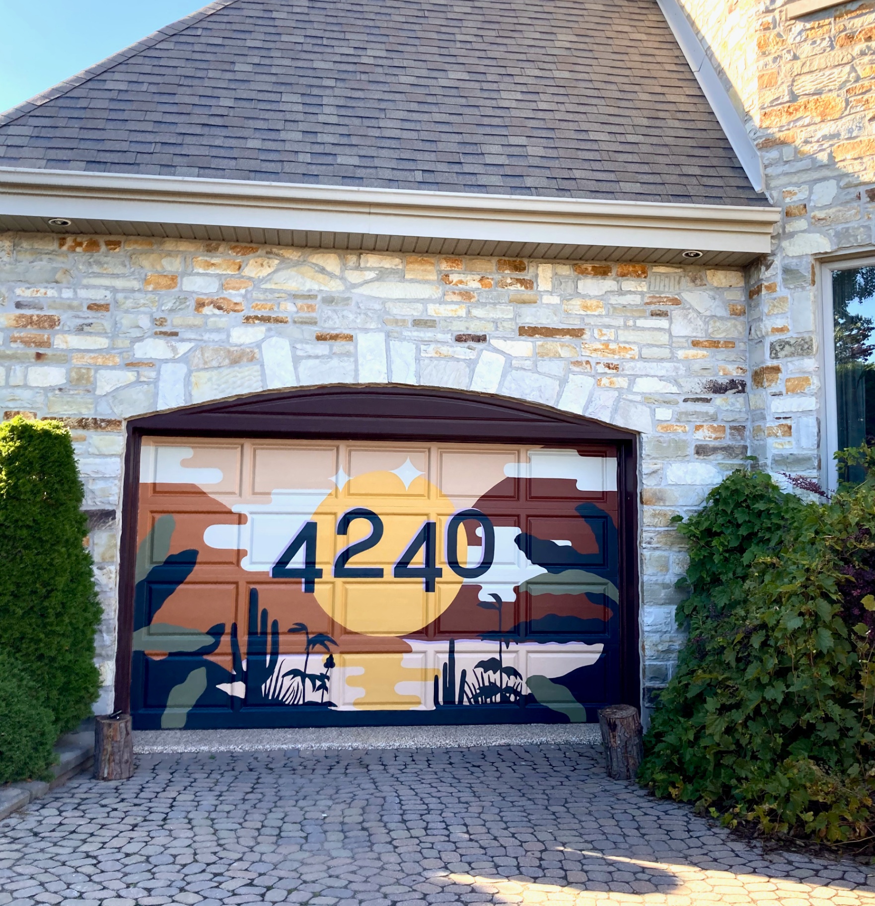 Murale artistique sur porte de garage à Montréal — paysage désertique au coucher de soleil, signature Magistrale